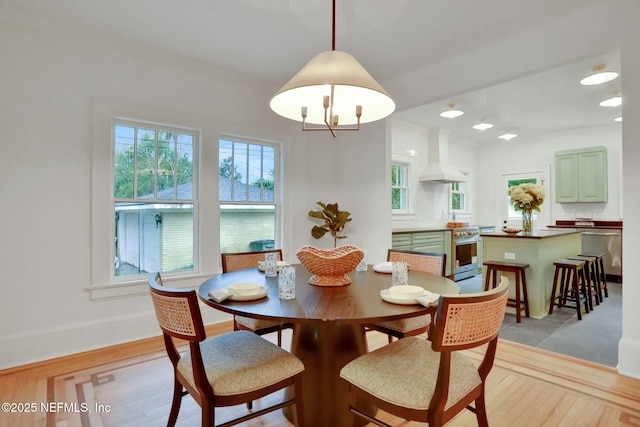 dining room featuring crown molding, light wood finished floors, and baseboards