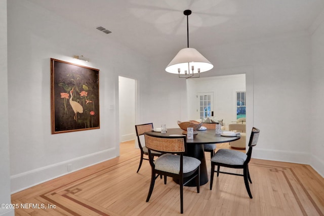 dining area with light wood-type flooring, visible vents, and baseboards