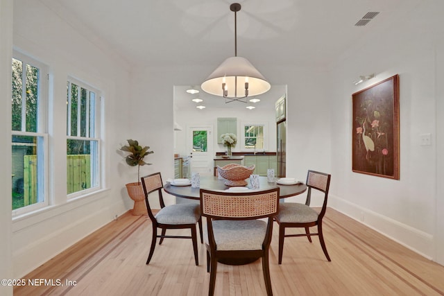 dining space featuring light wood-style flooring, visible vents, and baseboards