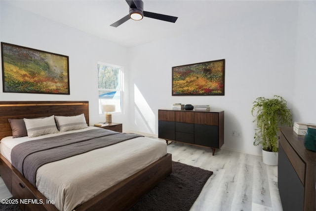 bedroom with light wood finished floors, baseboards, and a ceiling fan