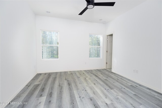 unfurnished room with a wealth of natural light, baseboards, ceiling fan, and wood finished floors