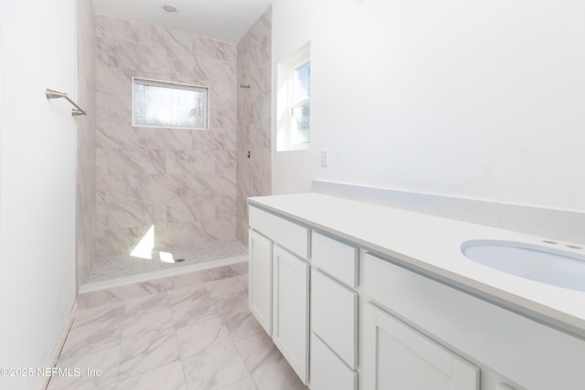 full bathroom featuring marble finish floor, a tile shower, and a sink