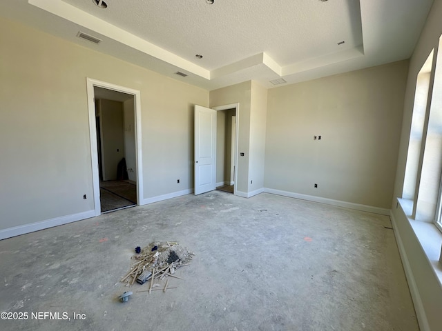 unfurnished bedroom featuring baseboards, a textured ceiling, visible vents, and a raised ceiling