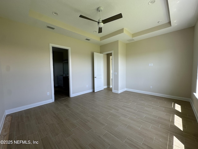 123 Tesoro Ter, Saint Augustine, FL 32095 - unfurnished bedroom with a raised ceiling, wood tiled floors, a ceiling fan, and a walk in closet