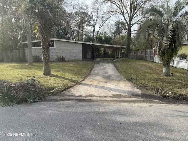 view of front facade with driveway, an attached carport, a front yard, and fence