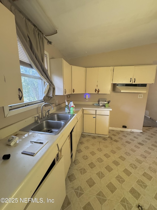 kitchen featuring light countertops, a sink, under cabinet range hood, and baseboards