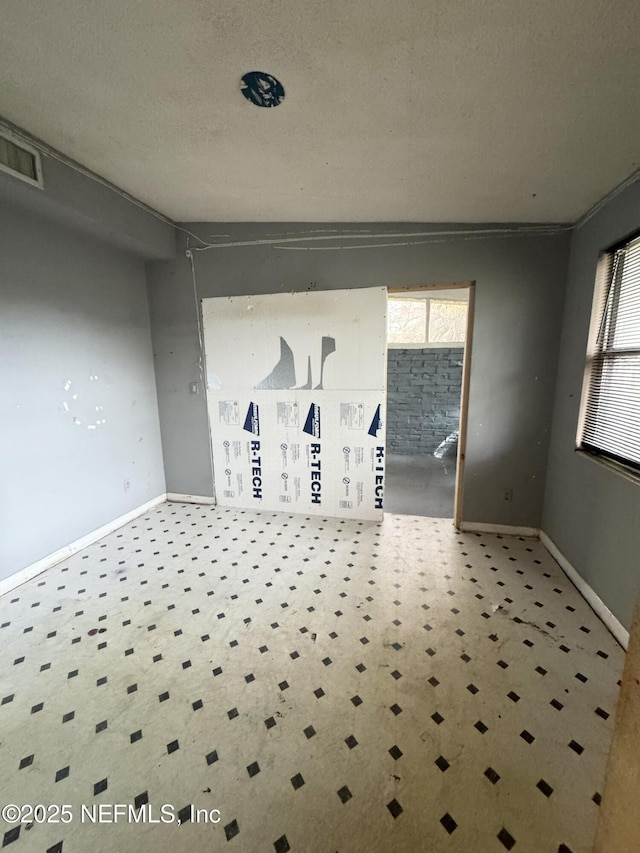 empty room featuring a healthy amount of sunlight, visible vents, and baseboards