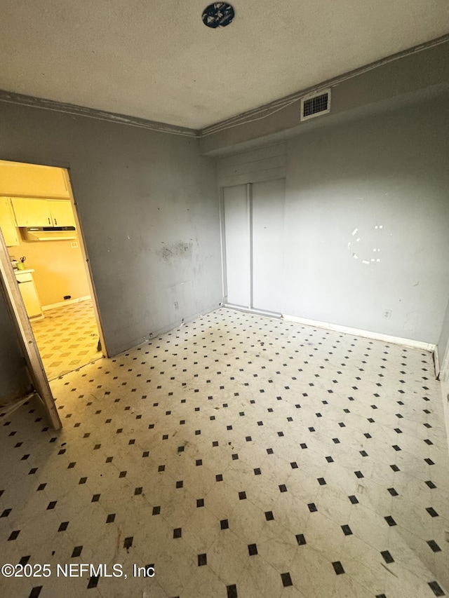 spare room with a textured ceiling, ornamental molding, and visible vents