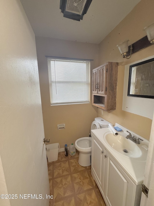 bathroom with baseboards, vanity, and toilet