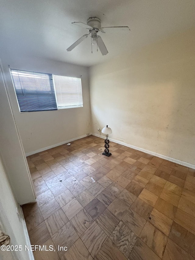 unfurnished room featuring a ceiling fan and baseboards