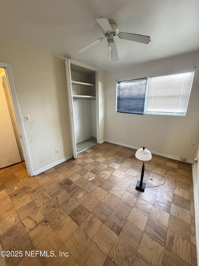 unfurnished bedroom featuring a ceiling fan, baseboards, and a closet