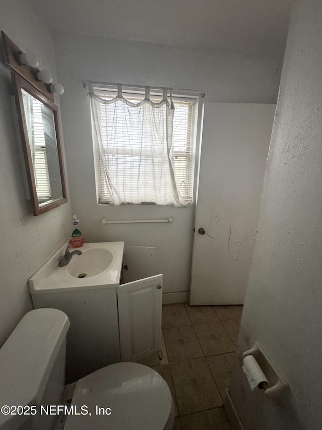 half bath featuring toilet, tile patterned floors, and vanity