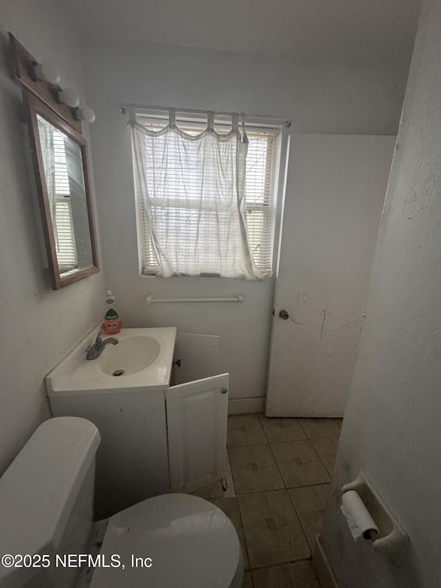 half bathroom featuring tile patterned flooring, vanity, and toilet