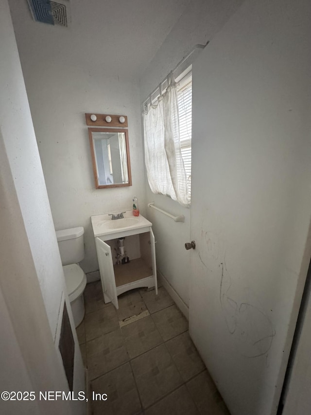 half bath with tile patterned flooring, visible vents, vanity, and toilet