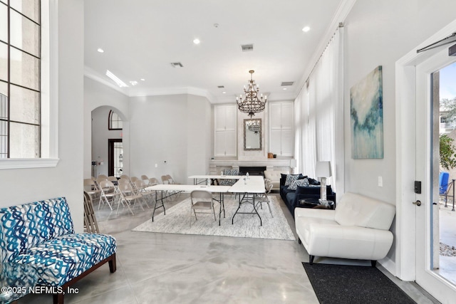 living area featuring visible vents, arched walkways, an inviting chandelier, crown molding, and concrete flooring