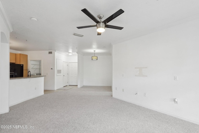 unfurnished living room with light colored carpet, crown molding, and ceiling fan