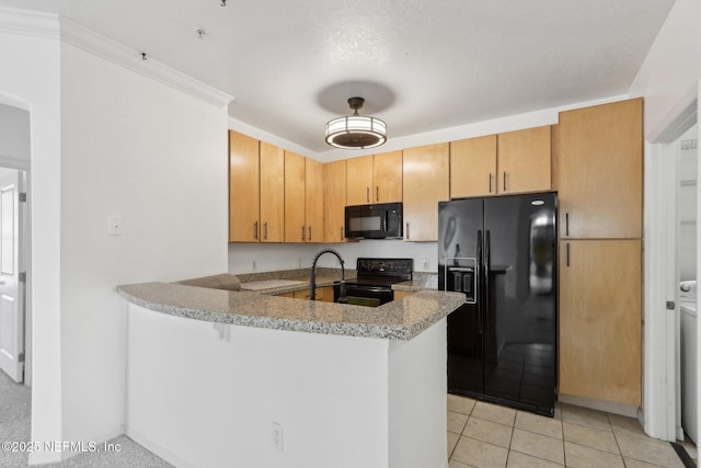 kitchen featuring black appliances, a sink, a peninsula, light tile patterned floors, and light stone countertops