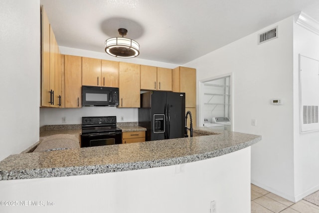 kitchen with visible vents, light tile patterned floors, a peninsula, independent washer and dryer, and black appliances