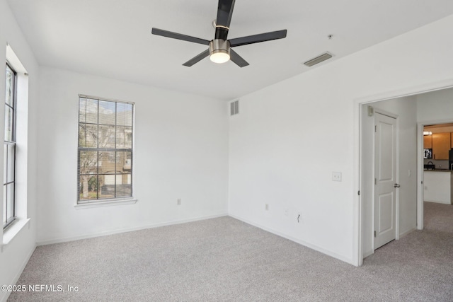 carpeted empty room with a ceiling fan, baseboards, and visible vents