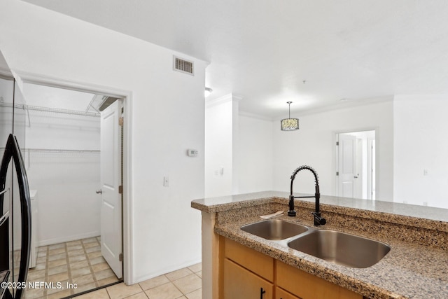 kitchen featuring visible vents, decorative light fixtures, ornamental molding, fridge, and a sink