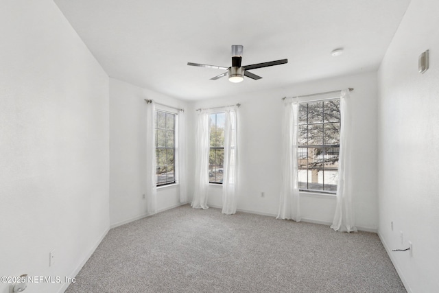 carpeted spare room featuring baseboards and a ceiling fan