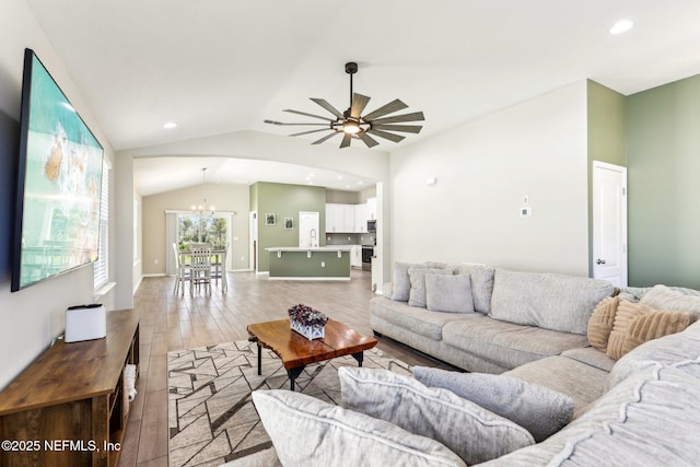 living area featuring baseboards, lofted ceiling, ceiling fan with notable chandelier, light wood-type flooring, and recessed lighting