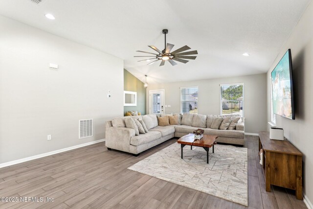 living room with lofted ceiling, visible vents, and wood finished floors