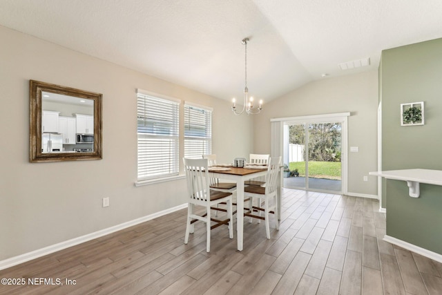 dining room with lofted ceiling, visible vents, an inviting chandelier, and wood finished floors