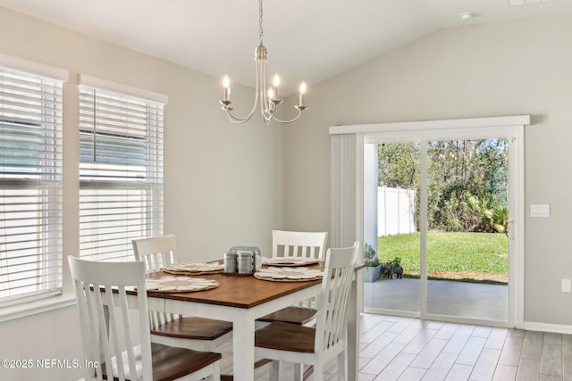 dining space with lofted ceiling, light wood-type flooring, a chandelier, and baseboards