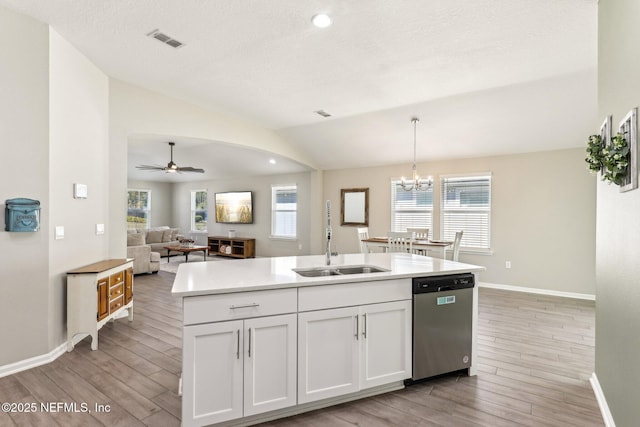 kitchen featuring a sink, visible vents, white cabinets, vaulted ceiling, and dishwasher