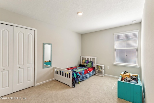 carpeted bedroom featuring a textured ceiling, a closet, and baseboards