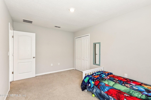 carpeted bedroom featuring a closet, visible vents, and baseboards