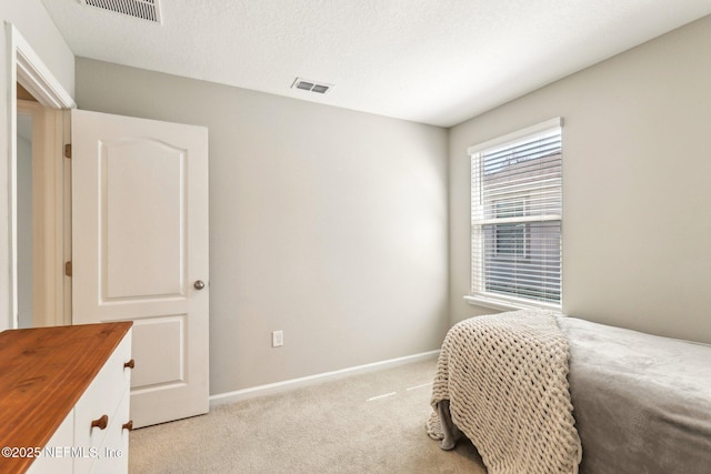 bedroom featuring light colored carpet, visible vents, a textured ceiling, and baseboards