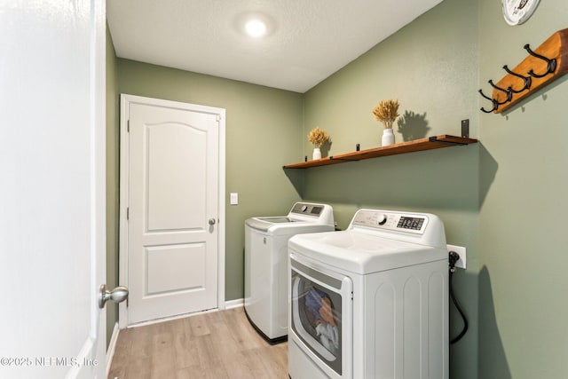 clothes washing area with a textured ceiling, laundry area, baseboards, light wood-type flooring, and independent washer and dryer