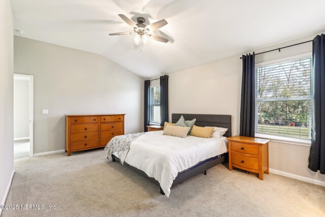 bedroom featuring light carpet, ceiling fan, baseboards, and vaulted ceiling