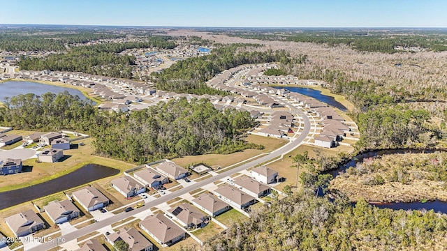 drone / aerial view featuring a forest view, a water view, and a residential view