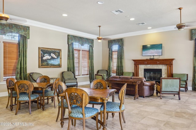 dining room with ornamental molding, a premium fireplace, visible vents, and baseboards