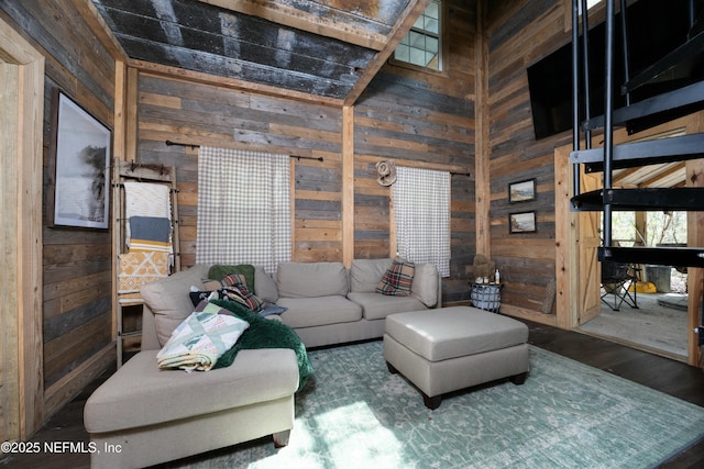 living area with wood walls, a towering ceiling, and wood finished floors