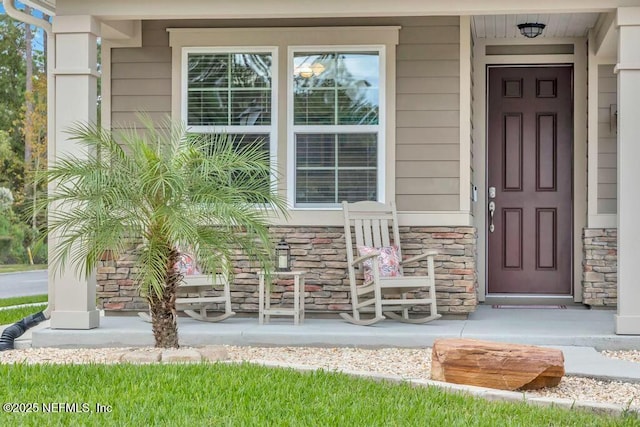 doorway to property with a porch and stone siding