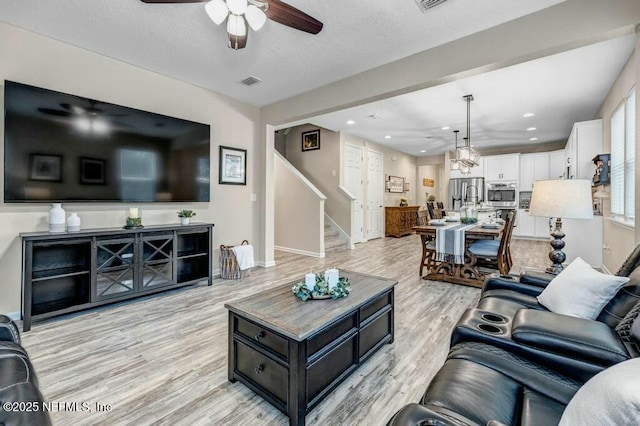 6743 Summit Vista Ct, Jacksonville, FL 32259 - living room with a textured ceiling, ceiling fan, visible vents, stairway, and light wood finished floors