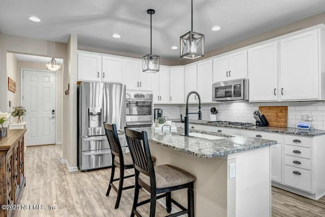 6743 Summit Vista Ct, Jacksonville, FL 32259 - kitchen featuring light wood finished floors, decorative backsplash, appliances with stainless steel finishes, a sink, and light stone countertops