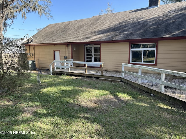 back of property with cooling unit, a yard, a chimney, a shingled roof, and a deck