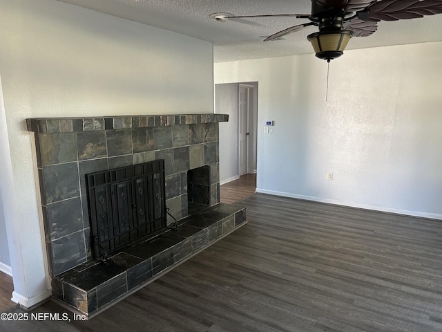 unfurnished living room with a ceiling fan, a textured ceiling, wood finished floors, a fireplace, and baseboards