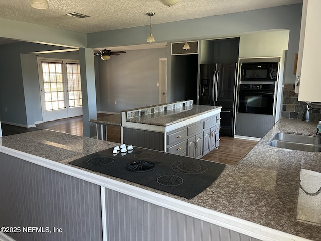 kitchen featuring visible vents, black appliances, a sink, dark wood-style floors, and ceiling fan