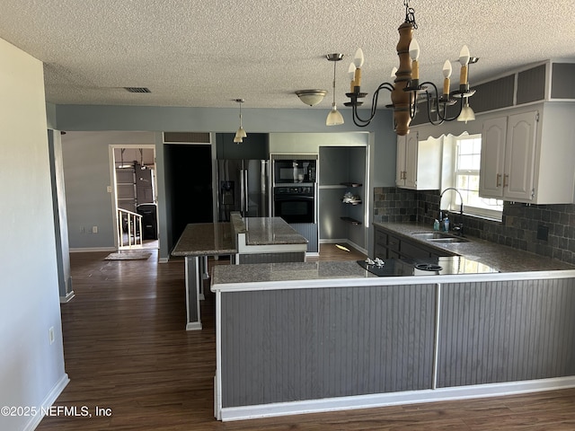 kitchen with a kitchen island, a sink, black appliances, dark wood-type flooring, and backsplash