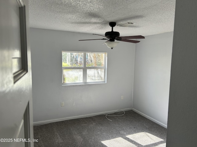 carpeted empty room with visible vents, a textured ceiling, baseboards, and ceiling fan