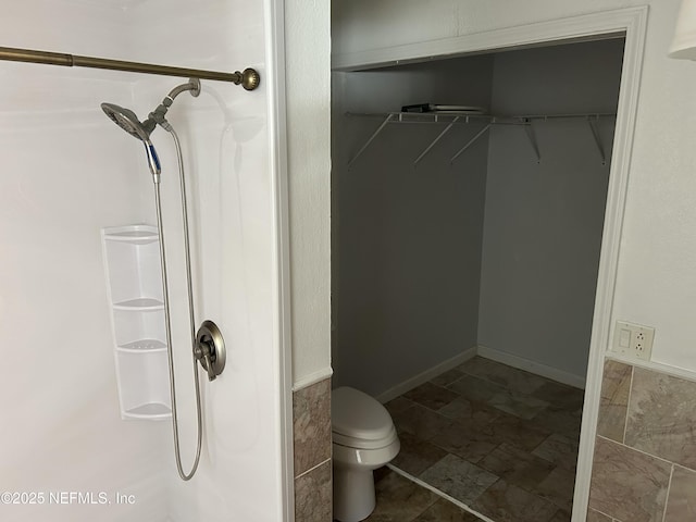 full bathroom featuring a spacious closet, toilet, and a shower