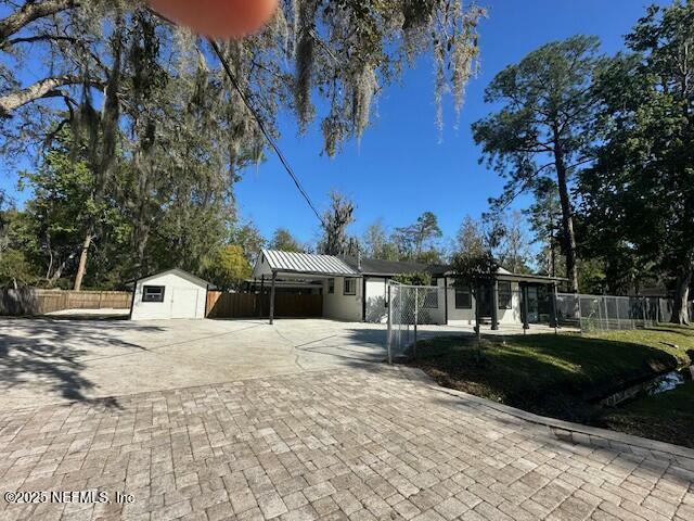 ranch-style home with decorative driveway, an outbuilding, a storage unit, and fence