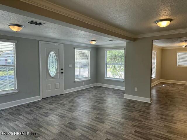 foyer entrance featuring visible vents, dark wood-type flooring, and ornamental molding