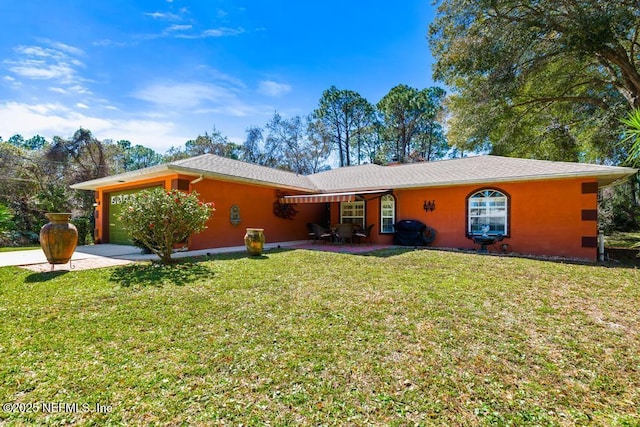 rear view of property with a yard, an attached garage, and stucco siding